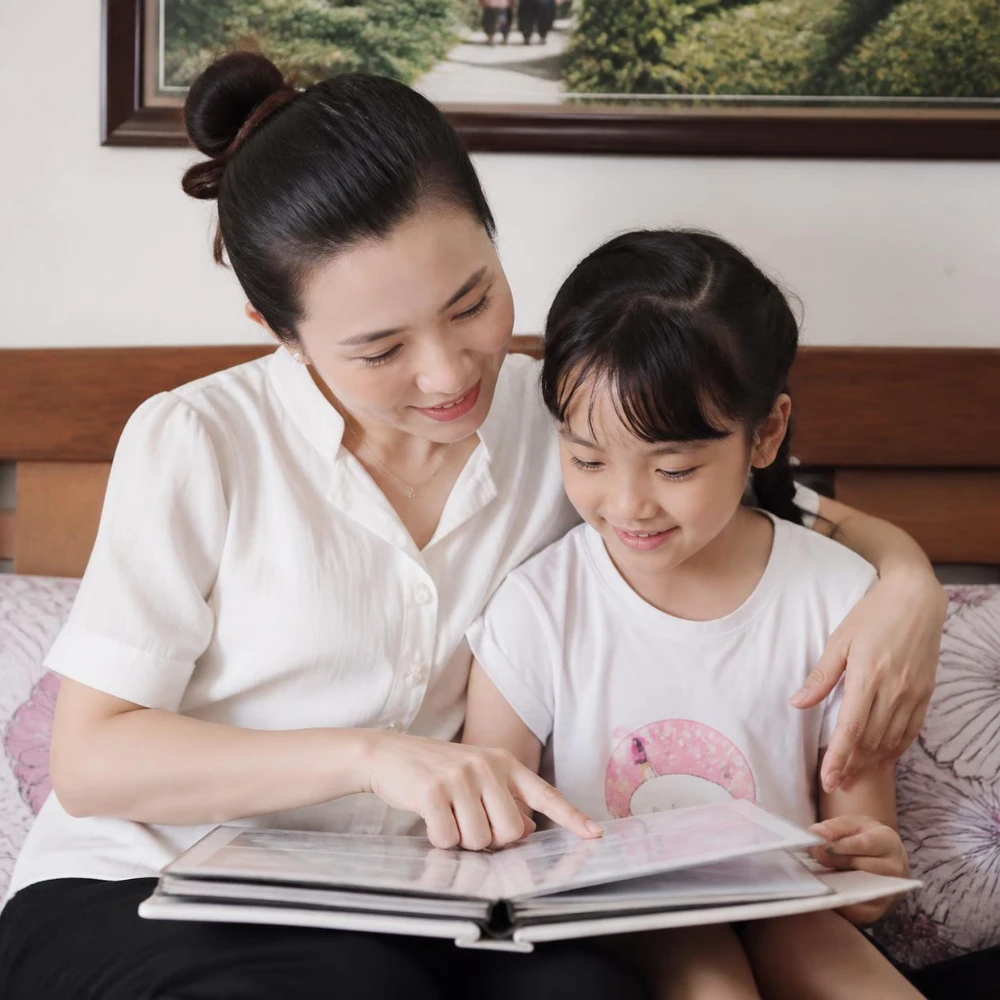 Mẹ ôm động viên và cùng con xem lại album ảnh kỷ niệm của gia đình. (Ảnh được tạo bởi AI)