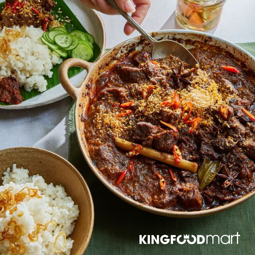 Rendang bò Indonesia màu nâu sẫm, cạnh đĩa cơm trắng nóng hổi.